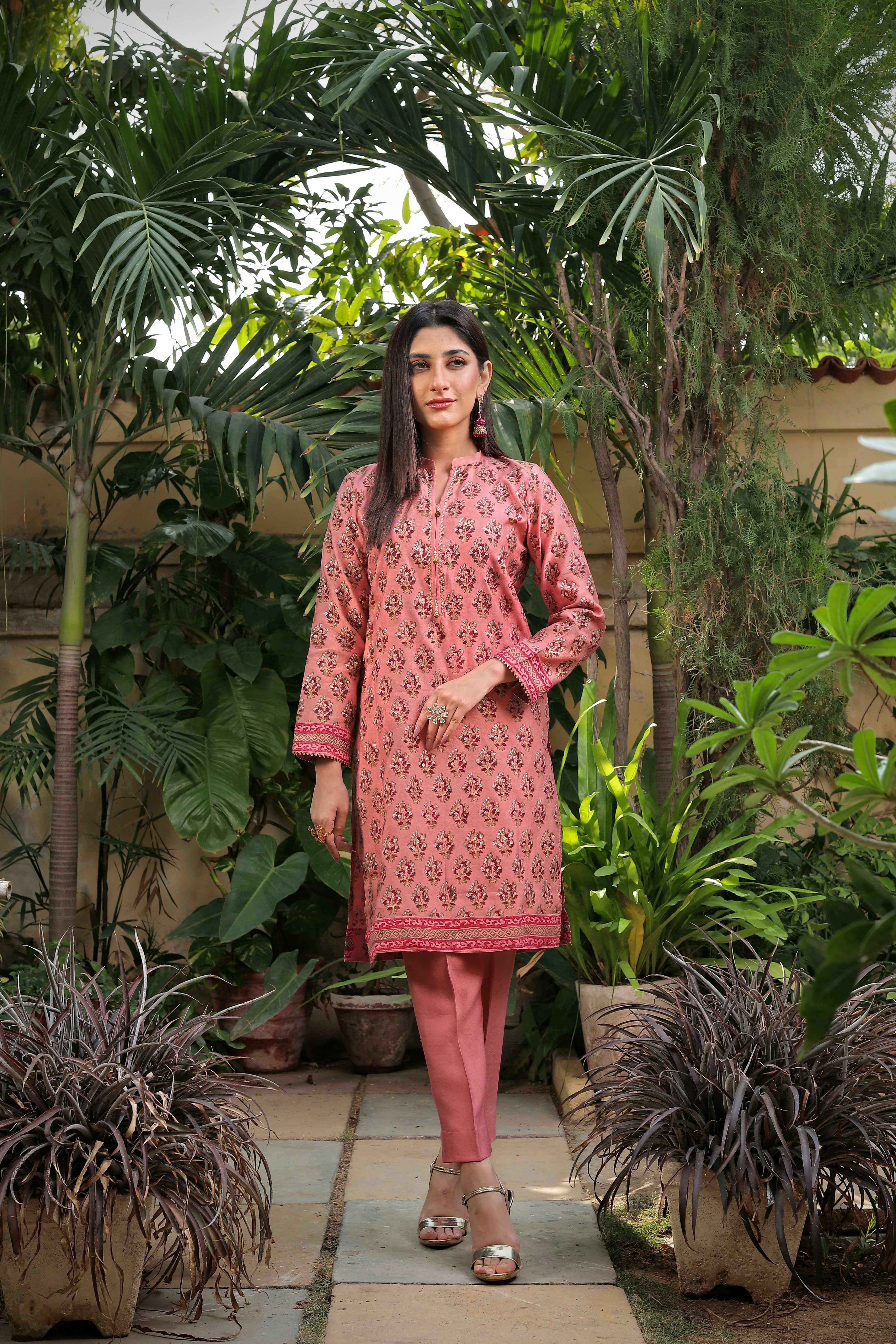 Woman wearing pink printed kurta with matching pants in garden setting